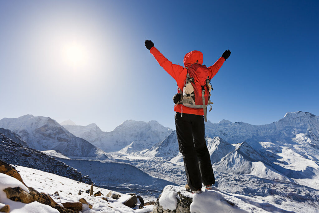 A person standing triumphantly at the top of a hill.