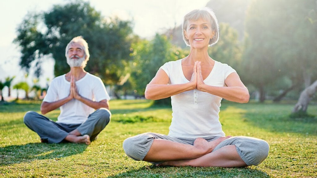 A lady and man joyfully meditating in a serene environment.